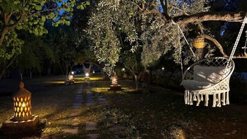 Un jardín con una silla mecedora, faroles y un sendero.