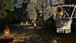 A garden with a swing chair, lanterns, and a pathway. - Villa Dar Serenity (Ounagha)
