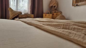 Un dormitorio con cama, ventana con cortinas y espejo en la pared.