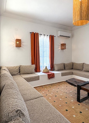 A modern living room with a sectional sofa, a coffee table, and a patterned floor.