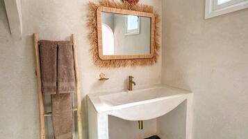Un baño con un lavamanos blanco, una escalera de madera y un espejo decorativo.