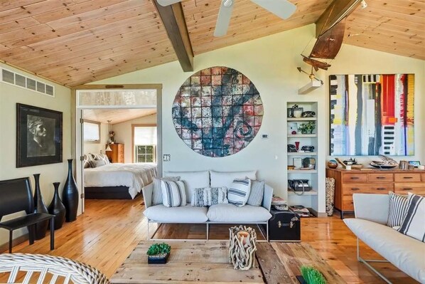 A spacious living area with a large round artwork on the wall, a wooden ceiling, and a cozy seating arrangement.