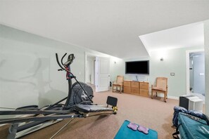 A room with a treadmill, a television, a desk, and a chair. - Lake Michigan Cottage - Sleeps 14 - Private Beach + Sunset Views (Harbor Springs)