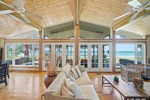 A spacious room with a high ceiling, large windows, and a view of the ocean.