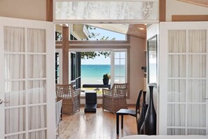 A room with a view of the sea, wicker furniture, and a potted plant.