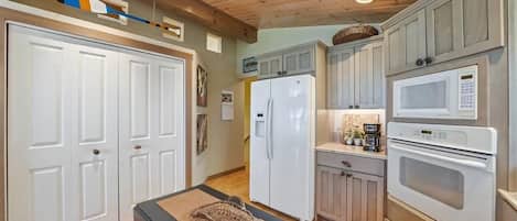 Una cocina con armarios de madera, un refrigerador, un microondas y un ventilador de techo.