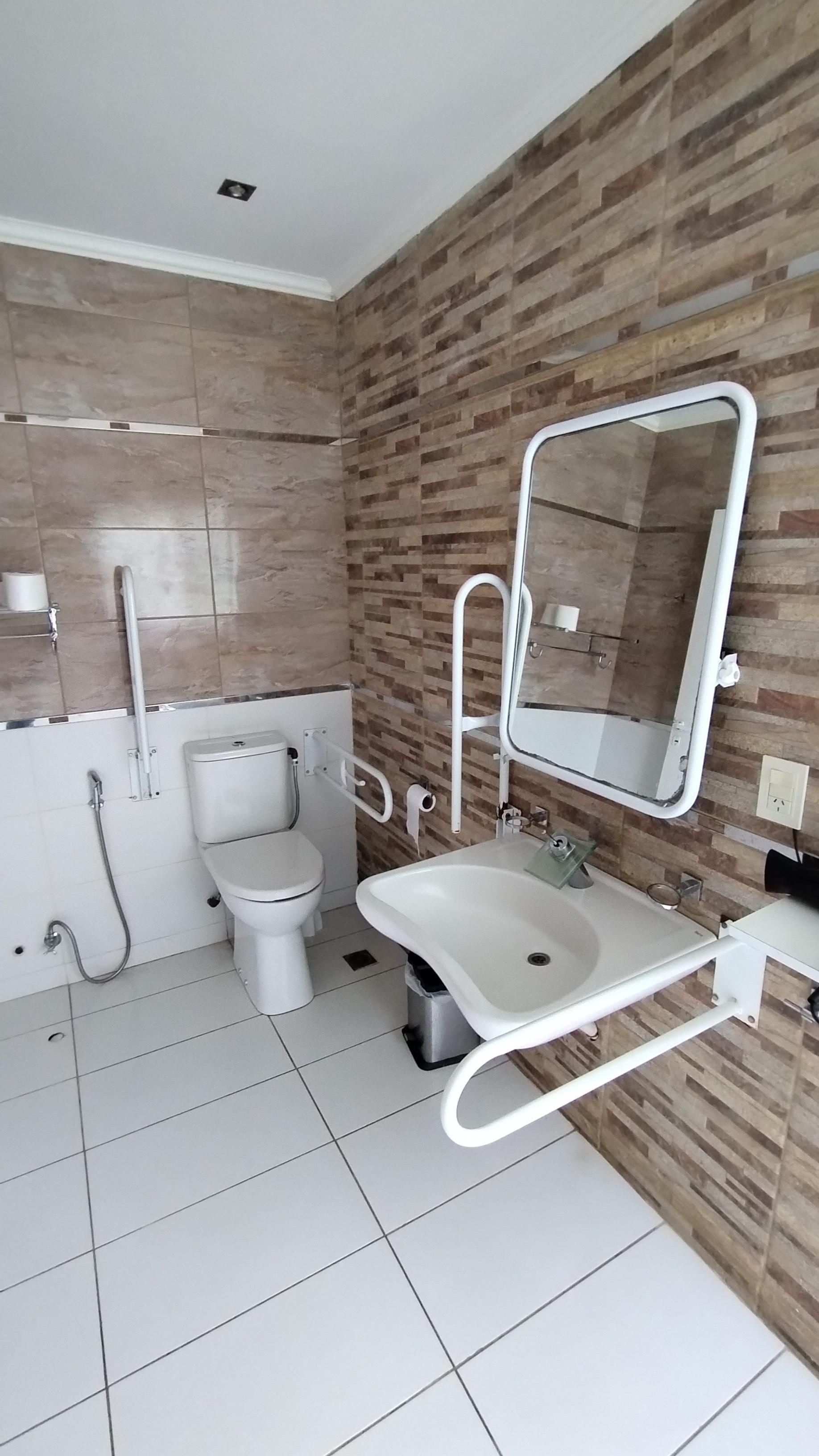 A modern bathroom with a toilet, sink, and mirror.