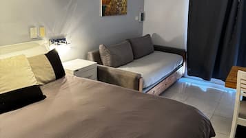 Un dormitorio con una cama grande, un sofá cama, una mesita de noche y un cuadro en la pared.