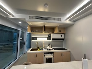 A compact kitchen with a built-in oven, a sink, and a small dishwasher. - 39-square-meter capsule house (Billdal)