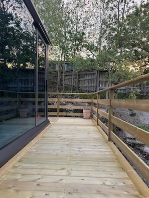 A wooden deck with a glass enclosure and a wooden fence. - 39-square-meter capsule house (Billdal)