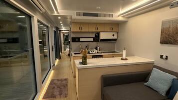A modern interior with a kitchen, dining area, and seating space, featuring a skylight and wooden flooring.