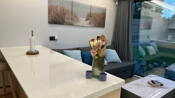 Et moderne opholdsrum med køkkenø, sofa og spiseplads.
