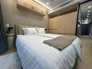 A modern bedroom with a bed, bedside tables, and built-in wardrobes.