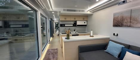 A modern kitchen with a skylight, a dining area, and a sofa with cushions.