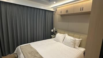 A bedroom with a skylight, a bed with white linens, a nightstand, and a view of trees through the window.