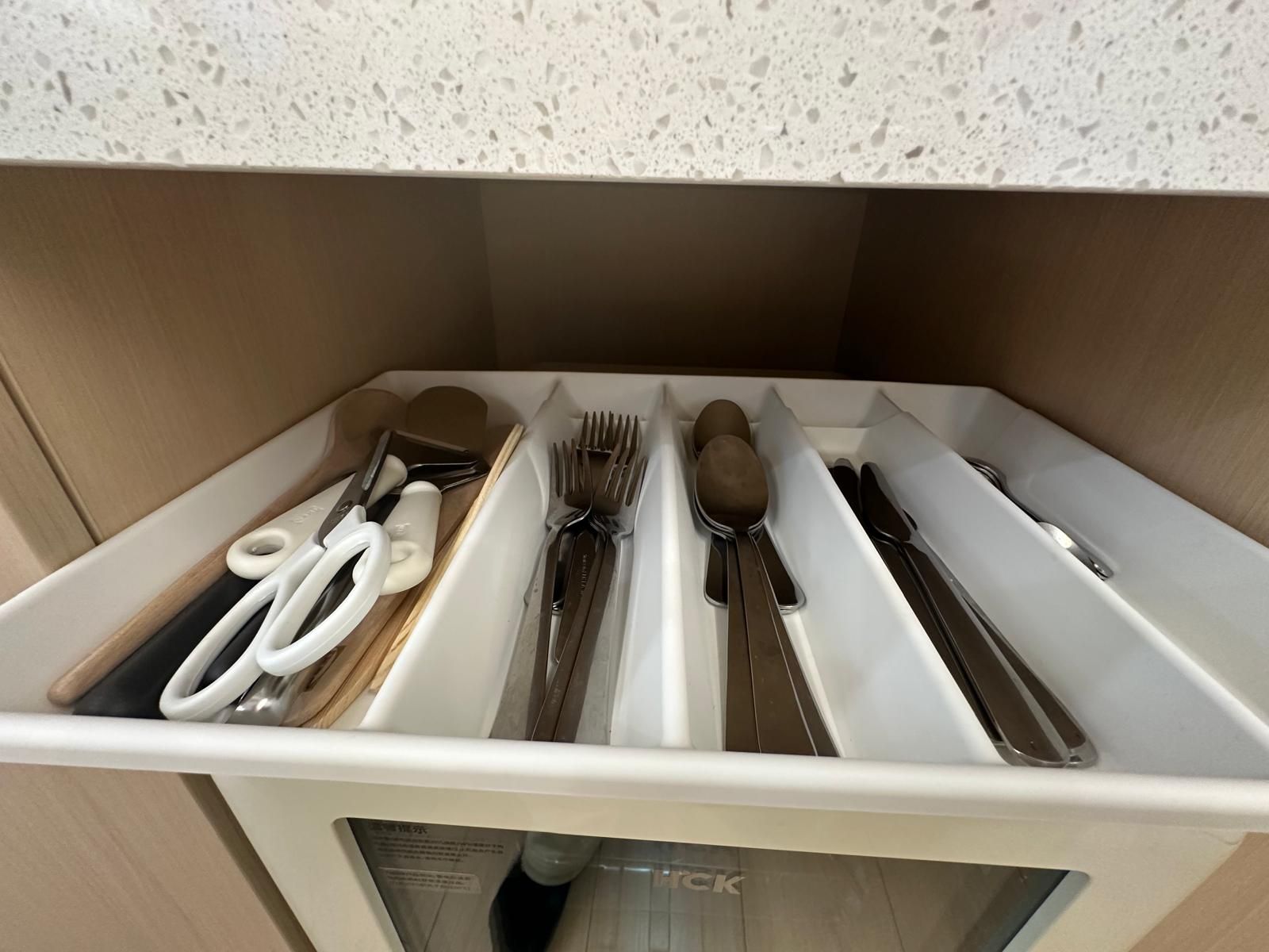 Un organizador de cajón con compartimentos para utensilios y un par de tijeras.