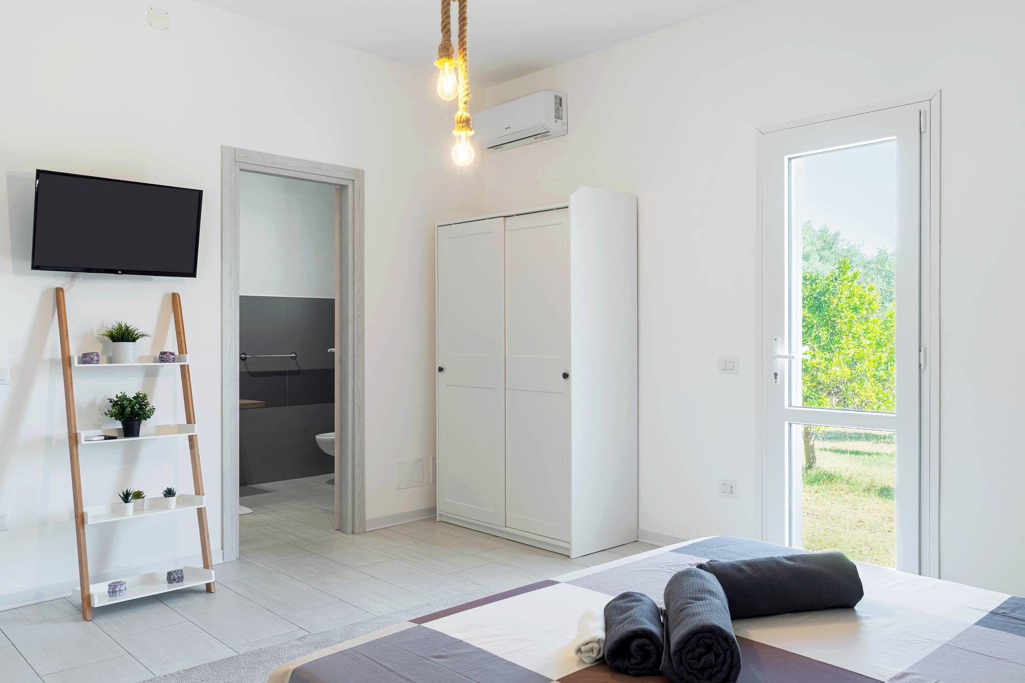 Une chambre moderne comprenant un lit, une télévision, une armoire, une salle de bain et un balcon.