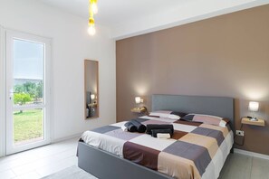 A modern bedroom with a large bed, bedside lamps, a mirror, and a view through a sliding door.