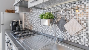 A modern kitchen with a gas stove, stainless steel sink, and a backsplash with a mosaic tile pattern. - Villa Latina with Private Veranda, Wi-Fi, and Air Conditioning (Solarino)