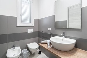 A modern bathroom with a toilet, bidet, and sink.