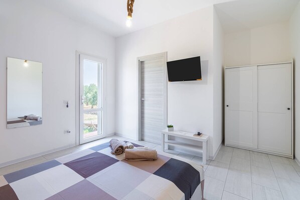 Ein Schlafzimmer mit einem Bett, einem an der Wand montierten Fernseher, einem Kleiderschrank und einem Fenster mit Blick.