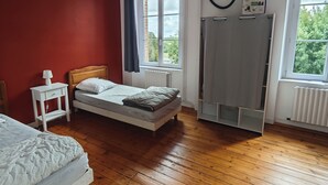 Ein Schlafzimmer mit Holzboden, einem Bett, einem Nachttisch, einem Kleiderschrank und einem Fenster mit Blick auf Grünflächen.