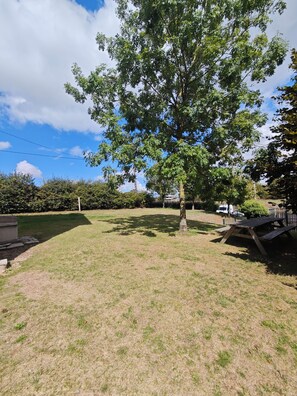 A grassy outdoor area with a picnic table and a tree. - Meurdrac's Rest (La Meurdraquière)