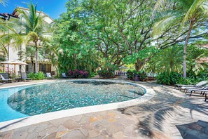 A pool with a stone border, surrounded by lounge chairs and palm trees. - Pacifico Townhome w/ 4 Resort Pools & Beach Club! (Sardinal)