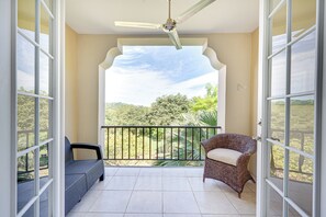 A balcony with a ceiling fan, a wicker chair, and a cushioned chair. - Pacifico Townhome w/ 4 Resort Pools & Beach Club! (Sardinal)
