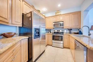 A modern kitchen with wooden cabinets, stainless steel appliances, and a granite countertop. - Pacifico Townhome w/ 4 Resort Pools & Beach Club! (Sardinal)