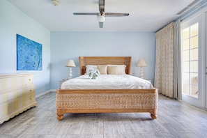 A bedroom with a large bed, two bedside lamps, a ceiling fan, a painting on the wall, and a window with curtains. - Pacifico Townhome w/ 4 Resort Pools & Beach Club! (Sardinal)