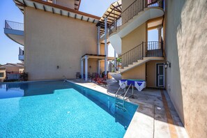 Ein Schwimmbad mit Sonnenterrasse, einer Treppe und Blick auf ein Nachbargebäude.
