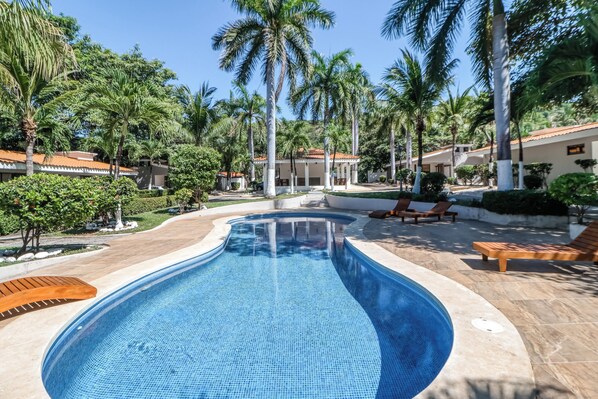A swimming pool with a tiled edge, surrounded by palm trees and lounge chairs. - Walk to Beach! Studio w/ Pool Access at Club Voca (Sardinal)