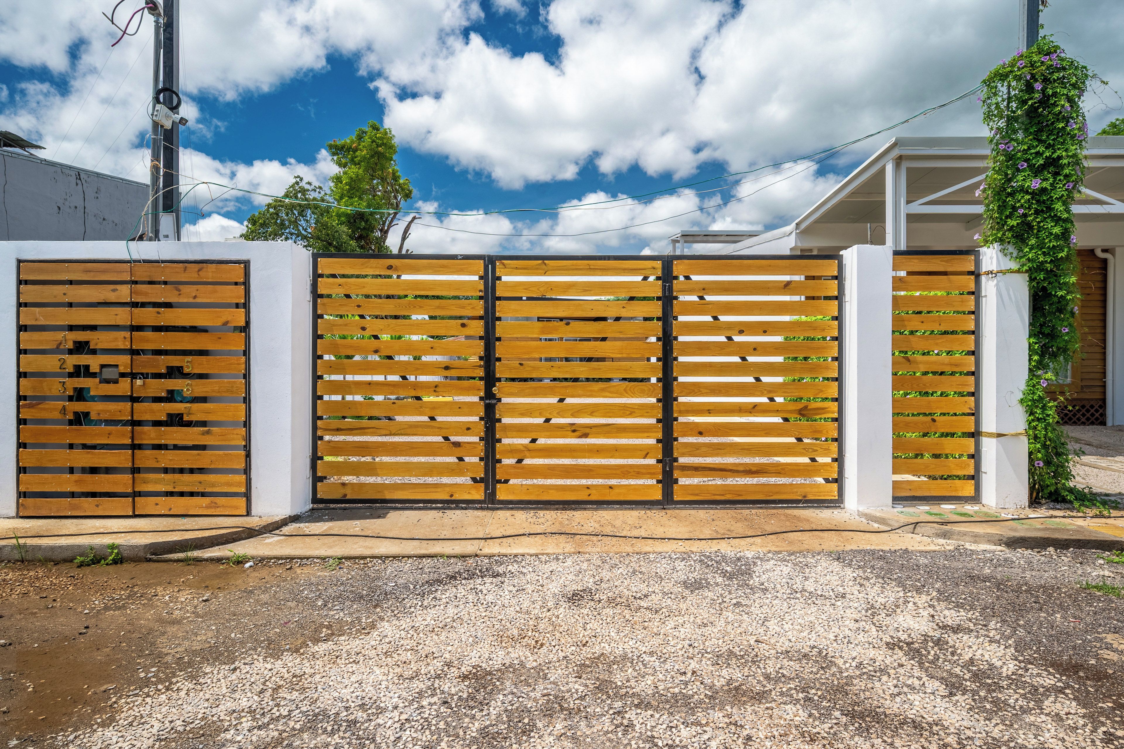 A gated entrance with a wooden fence and a white wall.