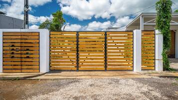 A gated entrance with a wooden fence and a white wall.