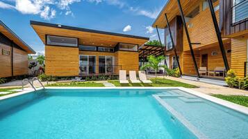 Un edificio moderno con piscina, mobiliario exterior y cielo despejado.