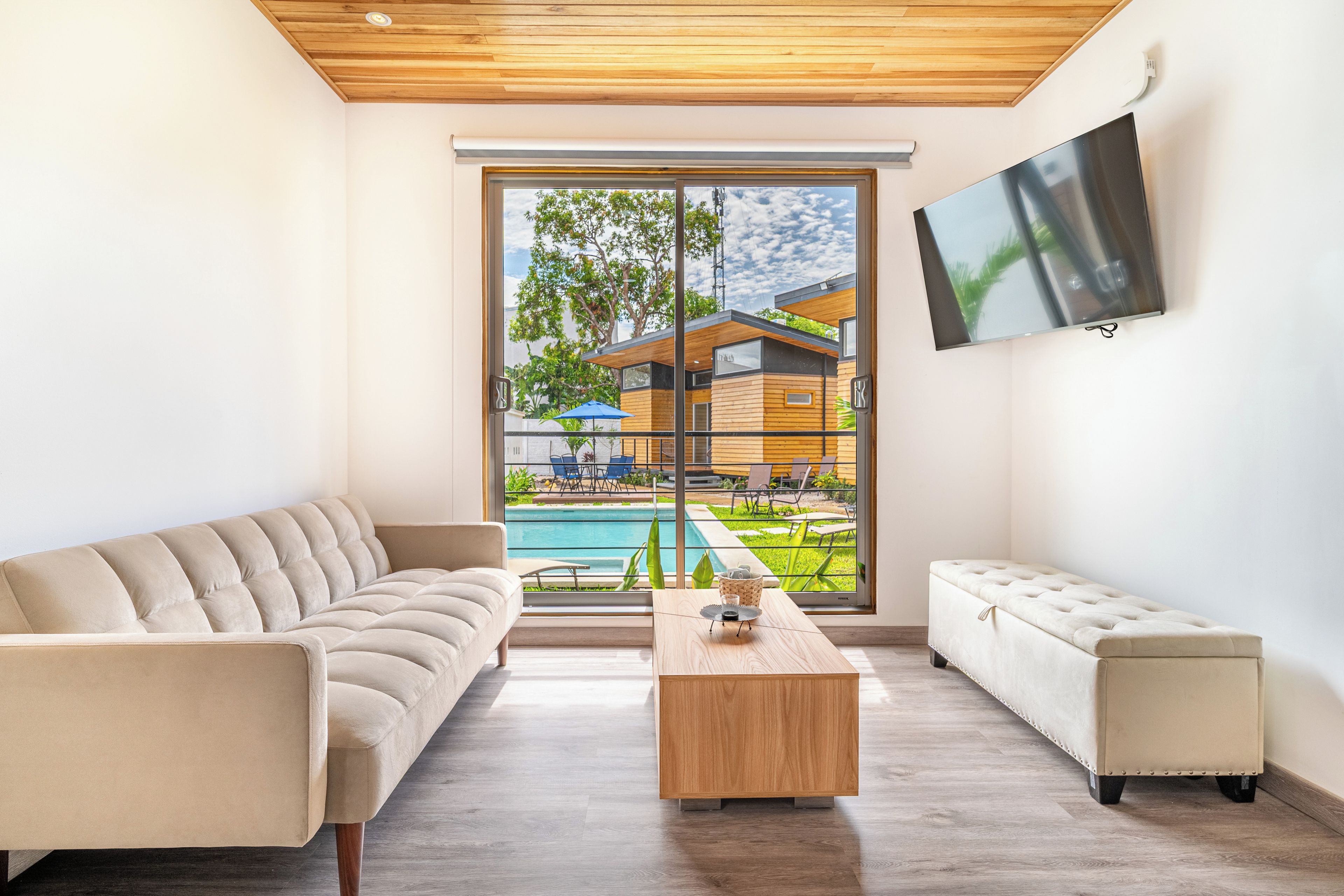 A modern living room with a sofa, a coffee table, and a TV mounted on the wall.