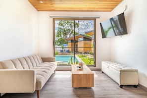 A modern living room with a sofa, a coffee table, and a TV mounted on the wall.