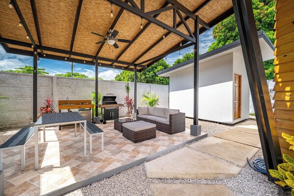 An outdoor patio with a table, chairs, a sofa, and a grill.