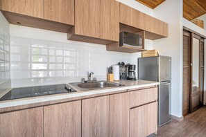 A modern kitchen with wooden cabinets, a stainless steel sink, a microwave, and a refrigerator. - Studio w/ Shared Pool < 1 Mi to Playas Del Coco! (Sardinal)