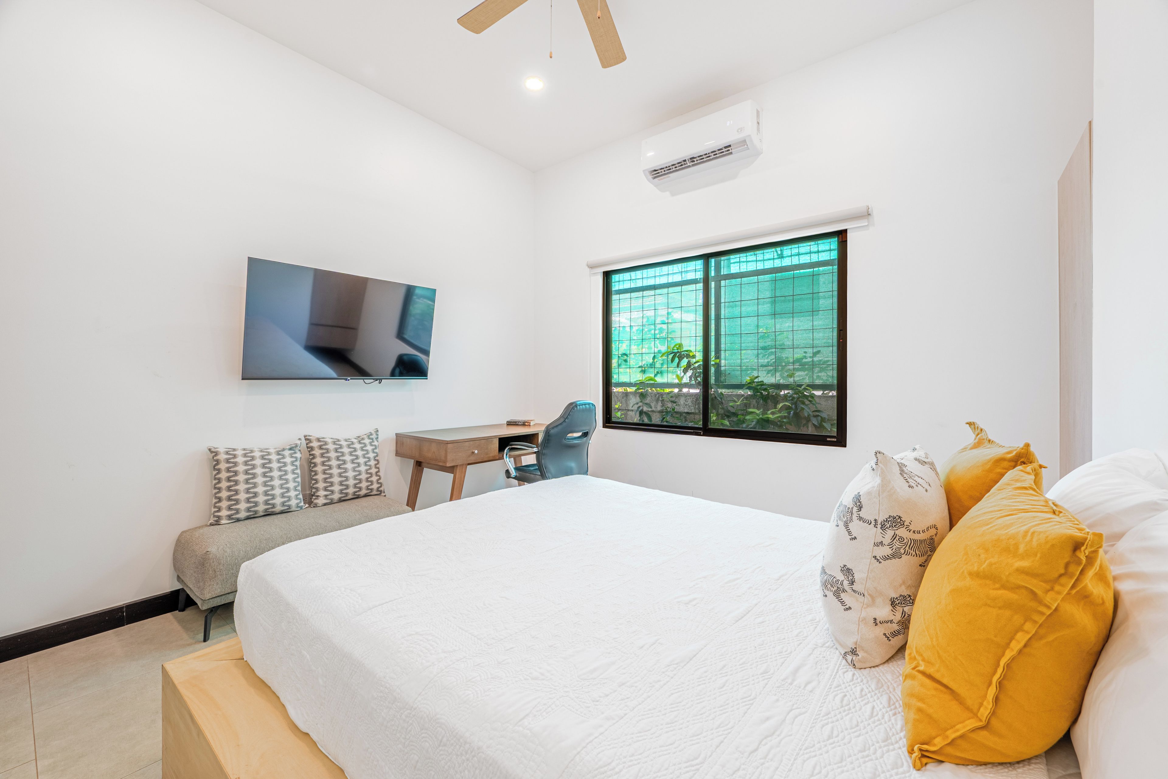 Une chambre à coucher avec un lit, un bureau, une chaise, une télévision et une fenêtre.