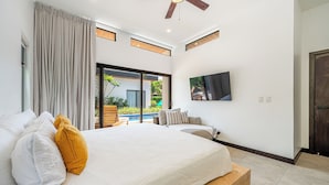 Quarto com cama, televisão e vista para uma piscina.