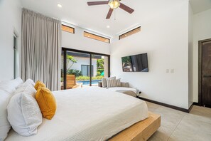 A bedroom with a bed, a TV, and a view of a pool. - Walk to Beach! Tamarindo Home w/ Private Pool (Tamarindo)