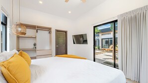Quarto com cama, guarda-roupa, televisão e vista para área externa.