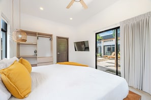 A bedroom with a bed, a wardrobe, a television, and a view of an outdoor area. - Walk to Beach! Tamarindo Home w/ Private Pool (Tamarindo)