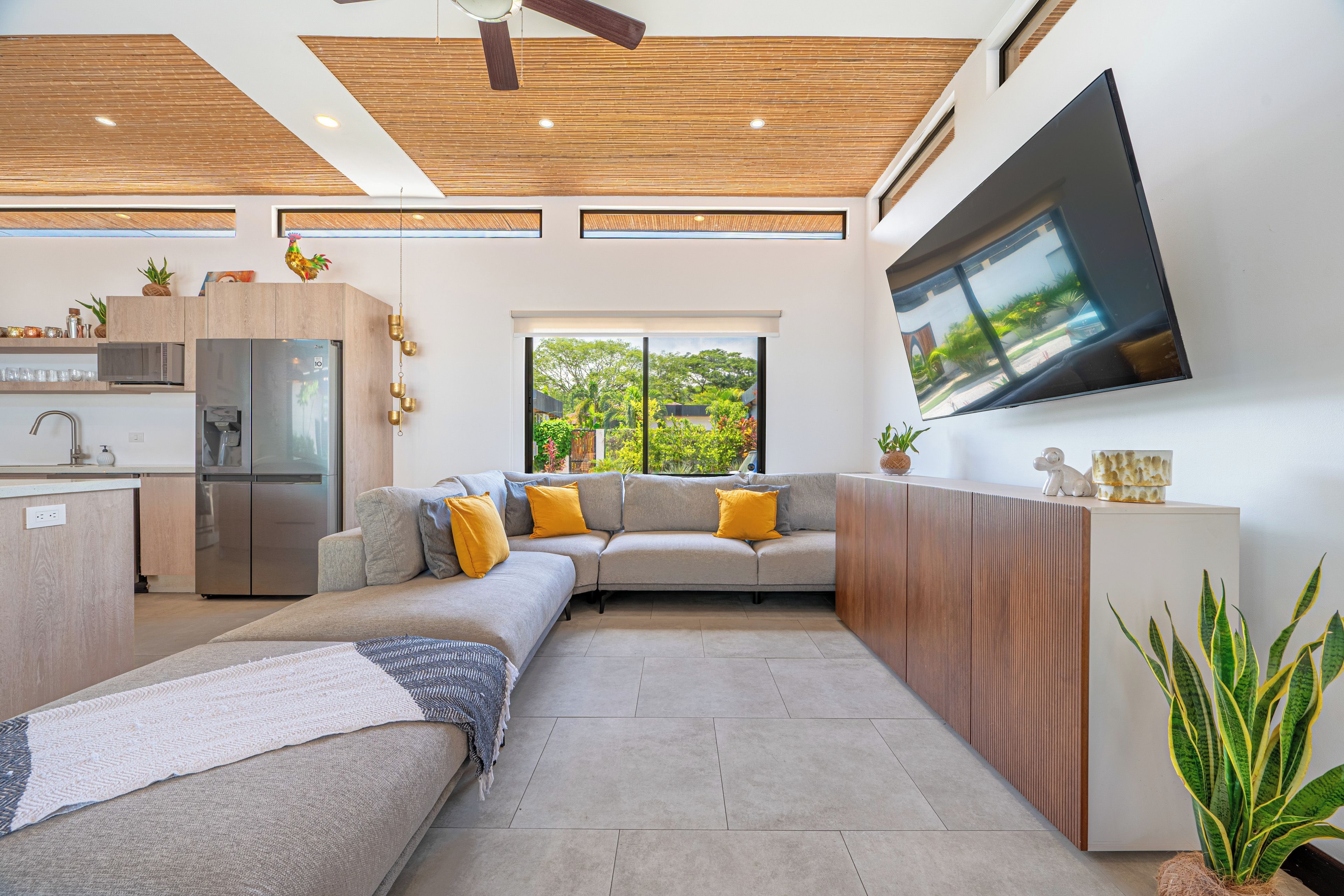 Eine moderne Küche mit integrierten Geräten, ein Essbereich mit einer Couch und ein großer Fernseher an der Wand.