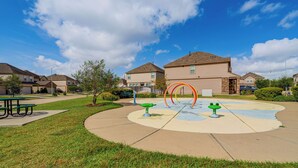 A residential area with houses, a playground with colorful equipment, and a picnic table.