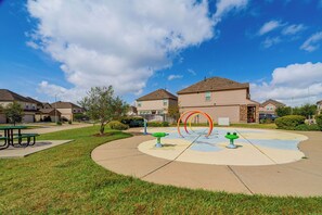 A residential area with houses, a playground with colorful equipment, and a picnic table.
