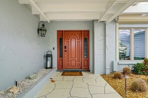 A red door with a glass panel, a stone pathway, and a small garden with pebbles and plants. - Bring Your Boat! Waterfront Clearwater Gem w/ Pool (Clearwater Beach)