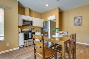 A modern kitchen with white cabinets, stainless steel appliances, and a dining table with wooden chairs. - 2 Mi to Downtown! Central San Antonio Rental (San Antonio)